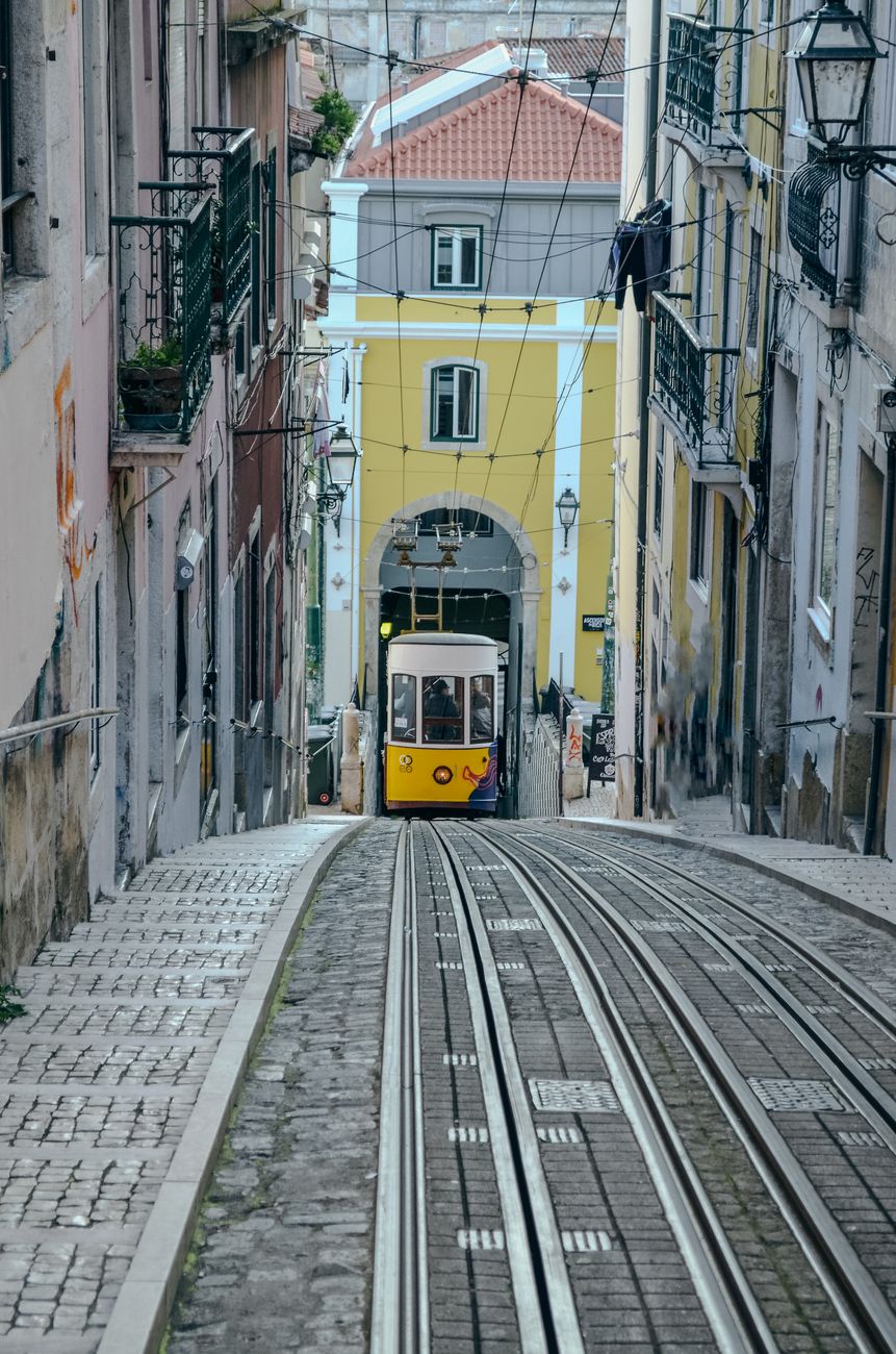 A classic yellow tram climbing a narrow Lisbon street